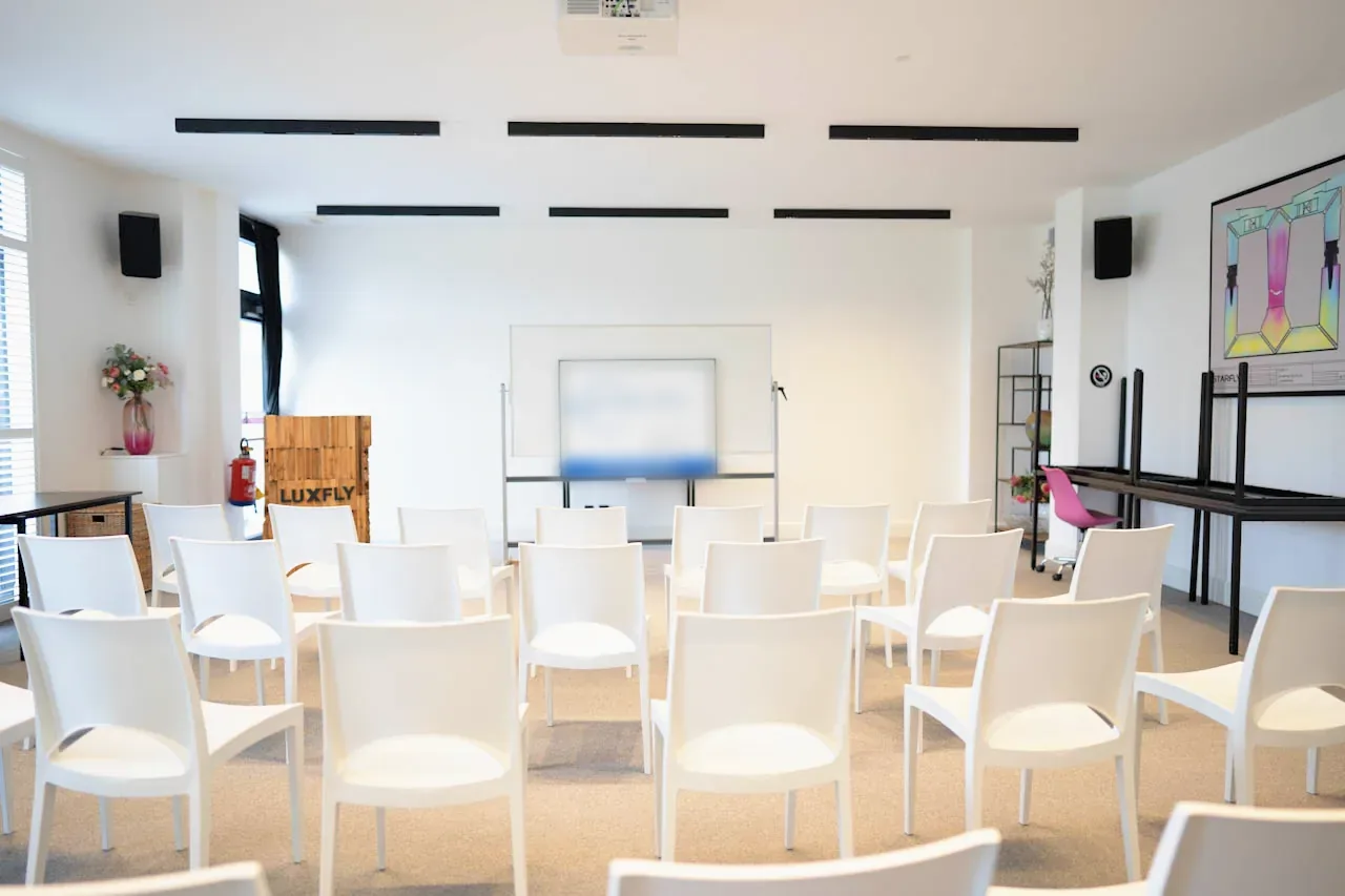 Salle de Luxfly avec rangées de chaises blanches, à la lumière du jour
