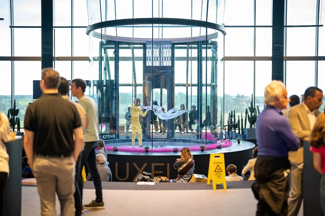 Visiteurs autour de la soufflerie vitrée dans le hall