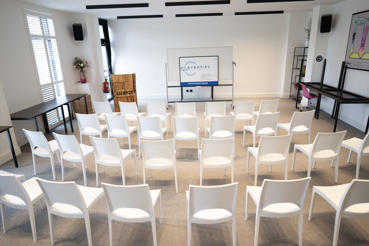 Rangées de chaises blanches face à l'écran de projection