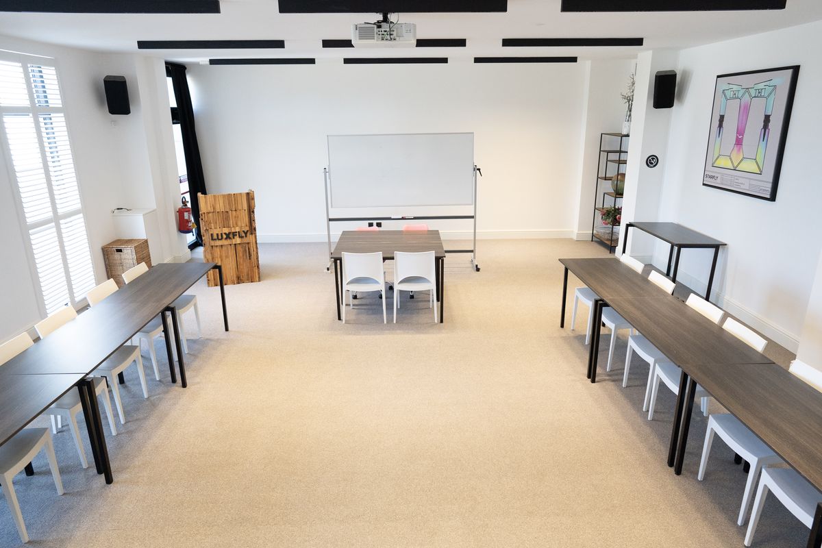 Salle en U, tables et chaises blanches face au tableau